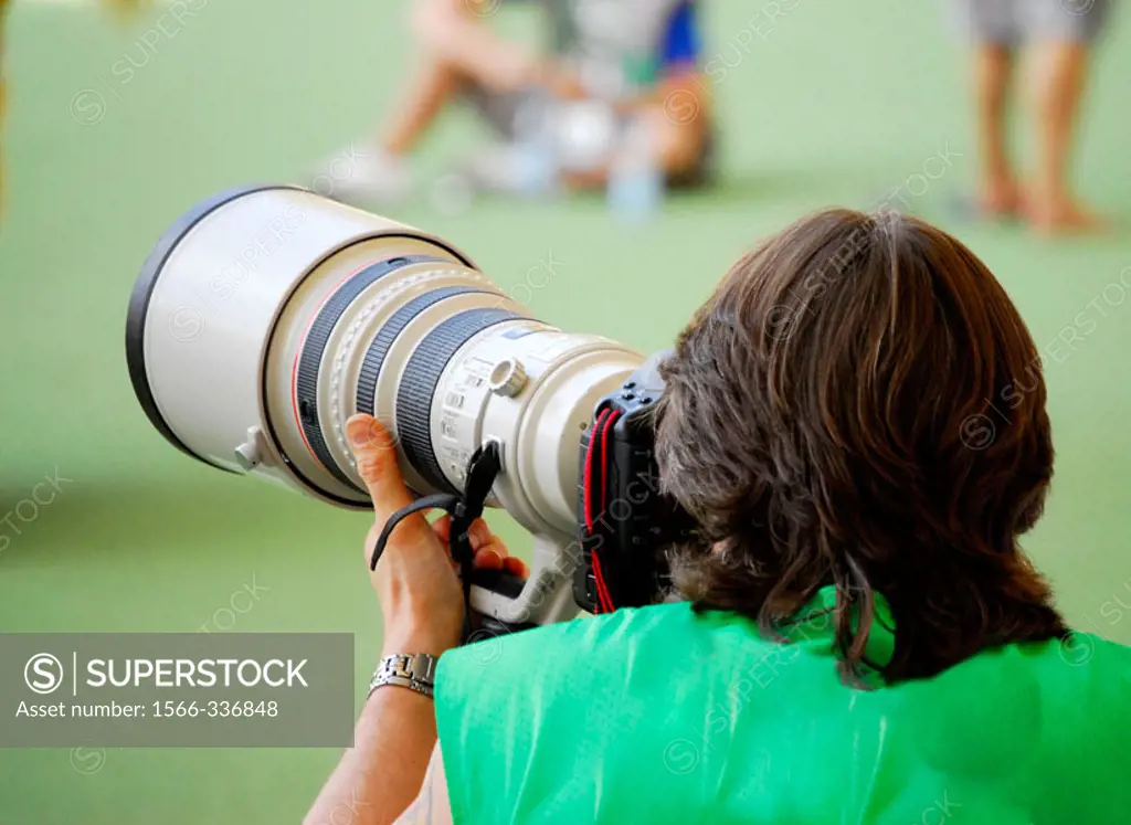 Professional sport photographer with a large telephoto lens in action.