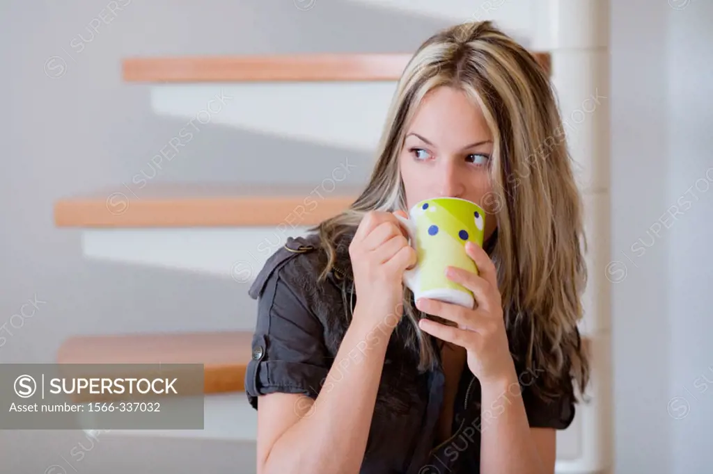 Cute girl drinking coffee while sitting on stairs