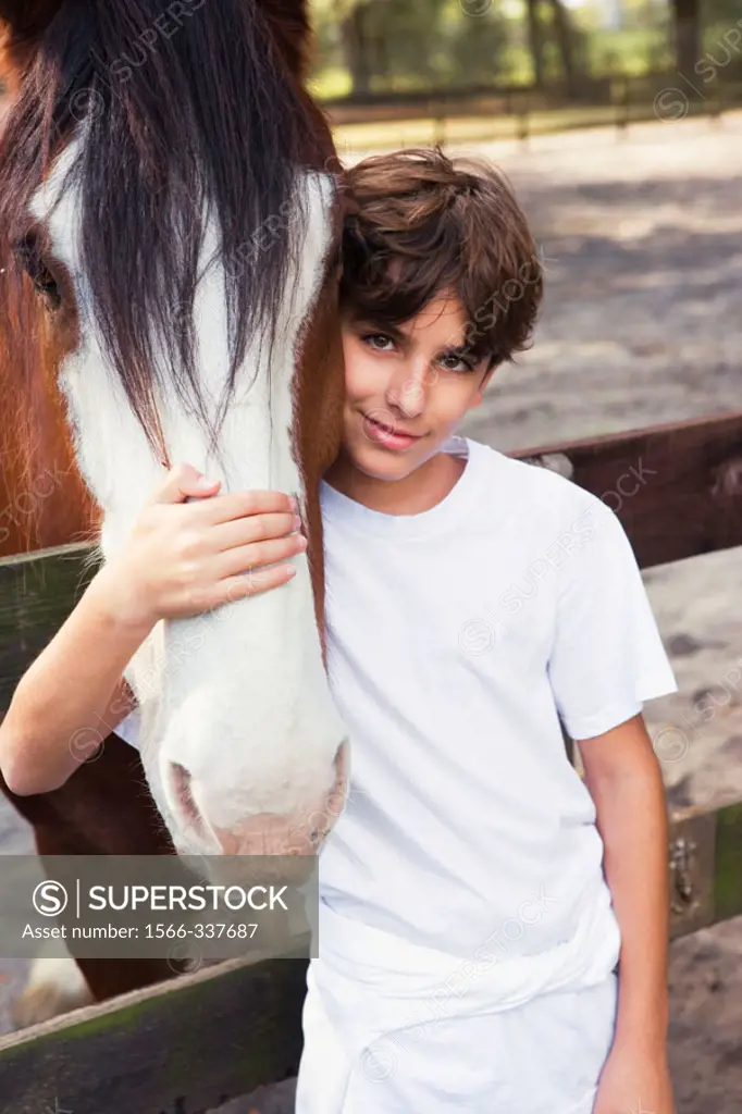 Boy embracing a clysdale horse face in a barn, Ocala, Florida