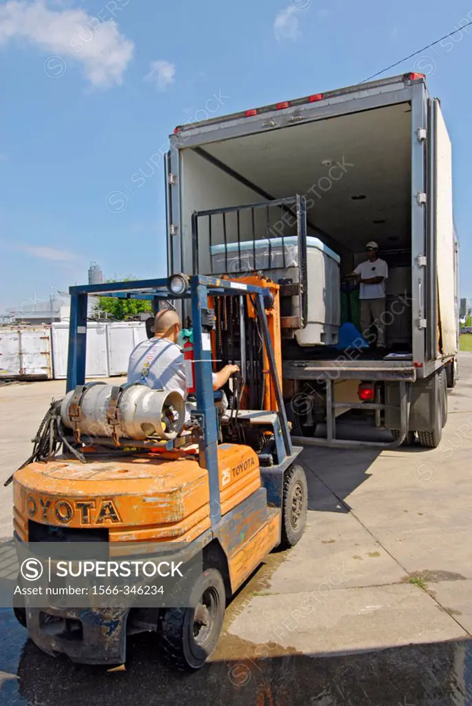 Forklift operator unloads a pallet of goods from a semi tractor trailer truck