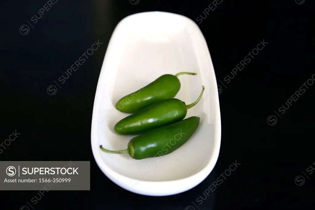Studio shot of chilli peppers on white tray, black background