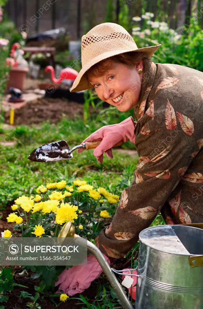 Senior woman planting flowers in garden.