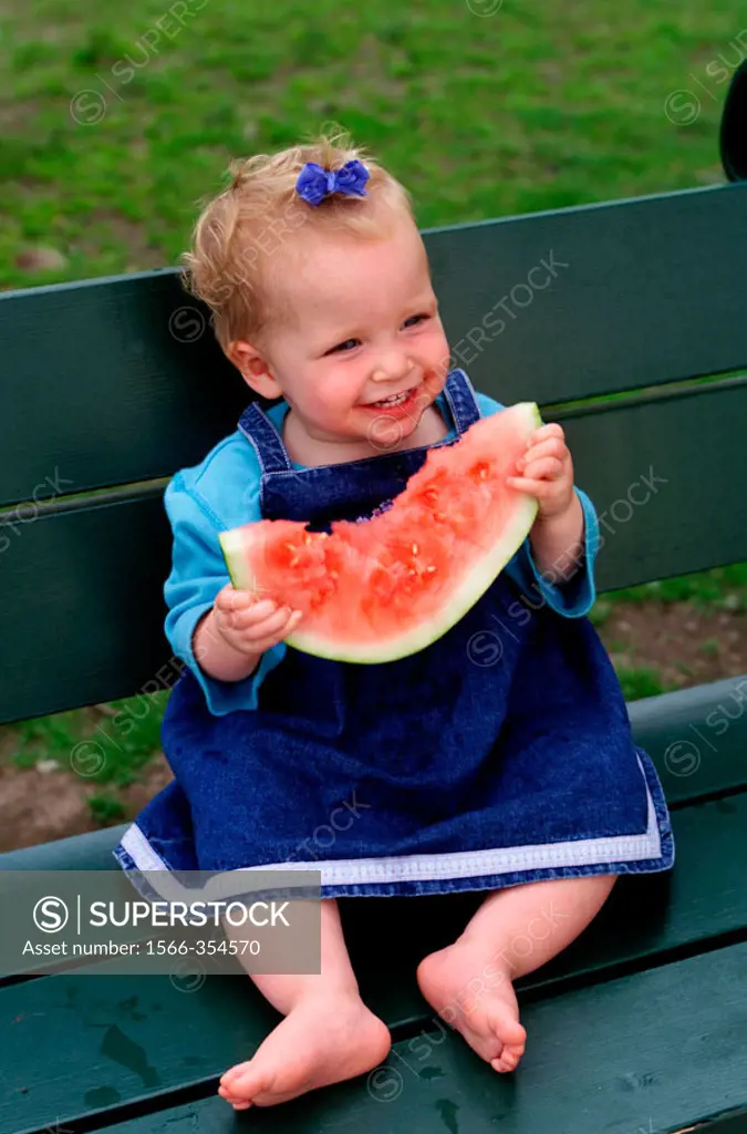 One year old baby girl eating watermelon.