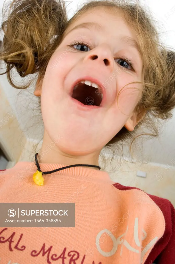 Little girl with pigtails bottom view makes a funny facial expression with the mouth open