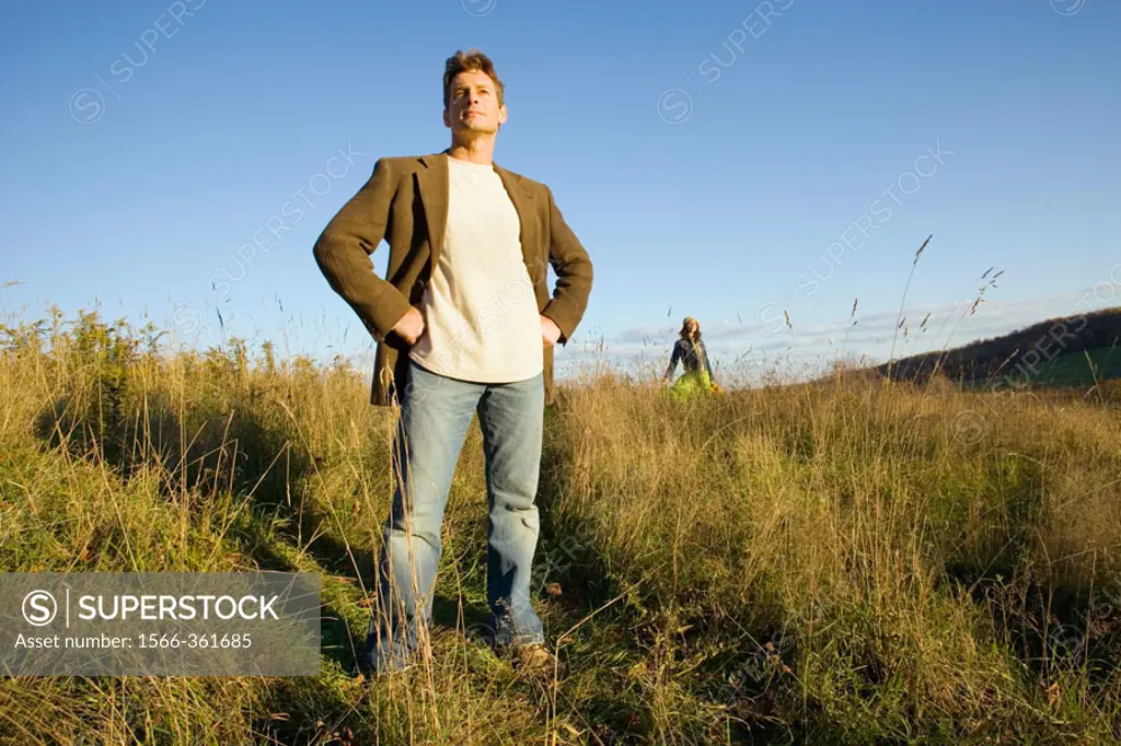 Man standing in field with woman in background