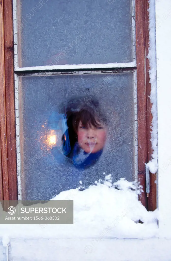 Winter, strong cold. Icy windows. 11 years old boy and a lantern.