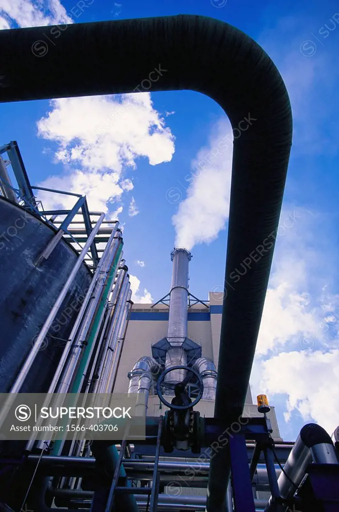 Paper industry, pulp mill, piping systems and valve, with smoking stack, against blue sky