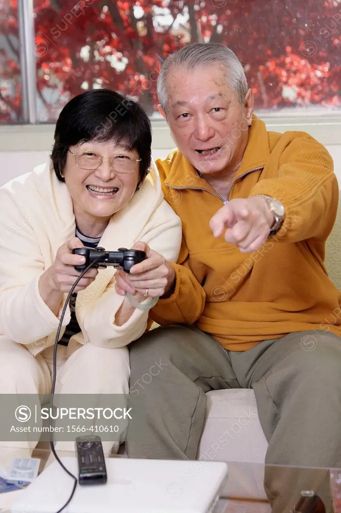 Senior Asian couple having fun playing video playstation games on tv