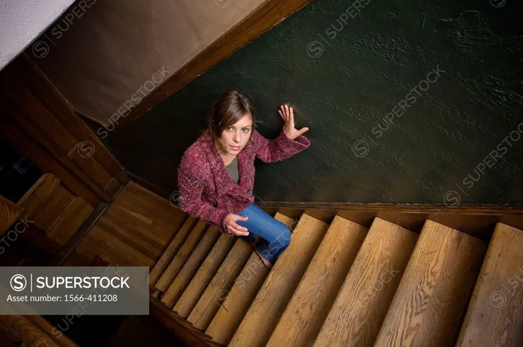 Young woman posing on the stairwell of her apartment building.