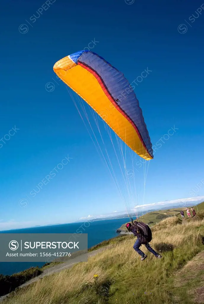 Man with paraglider hang glider taking off  from Constitution hill Aberystwyth over looking  Cardigan bay, Wales UK
