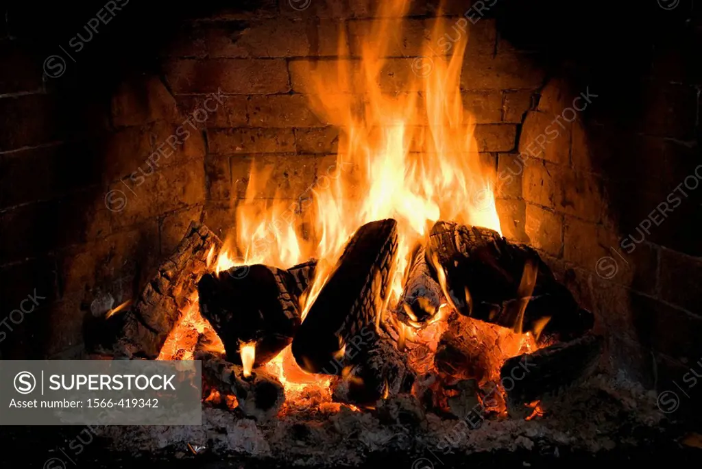 Log fire burning in an open brick fireplace