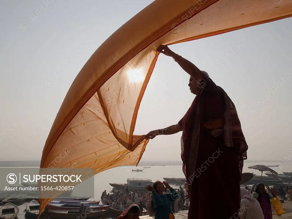 A woman dries a wet sari in the early morning sun after bathing in the Ganga river (in accordance with the Hindu belief that such bathing will wash aw...