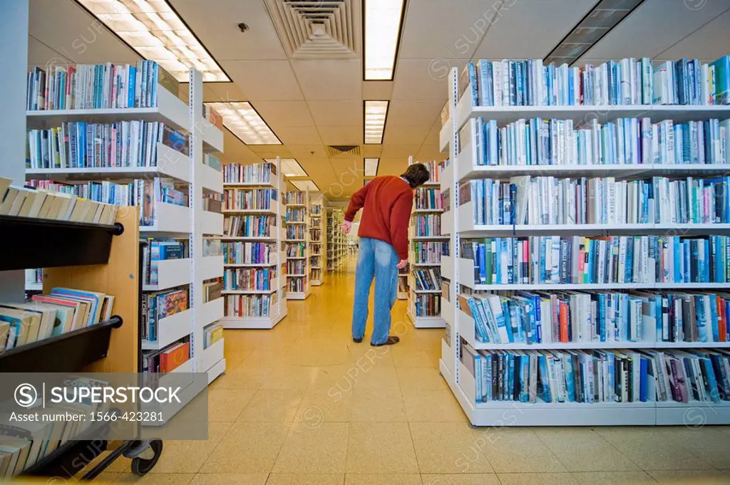 Man standing by bookshelves in a library