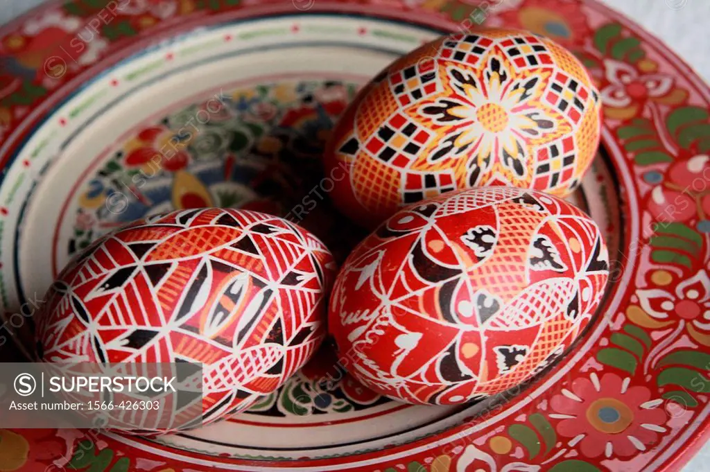 three red traditional Czech Easter eggs rest on a handpainted wooden Bohemian plate. The eggs have tradtional red geometrical design that is very popu...