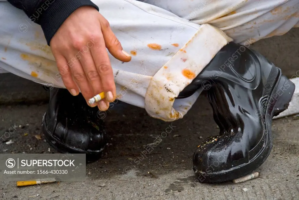 Seattle, Washington, USA: A chef takes a smoke break on the curb outside of a factory that processes food.
