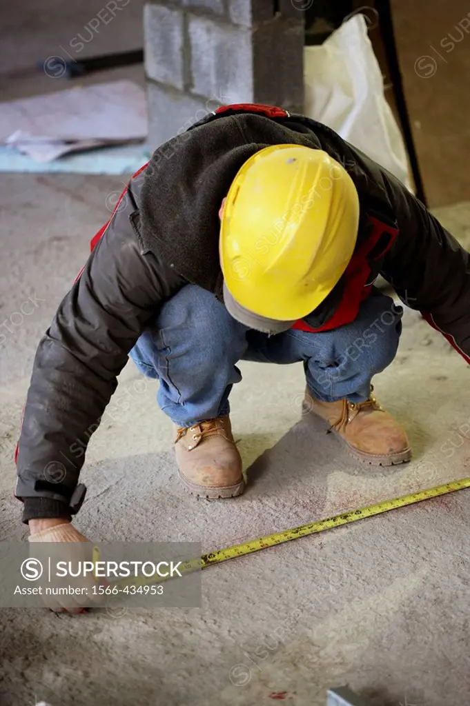 Construction worker taking marking measurement on floor
