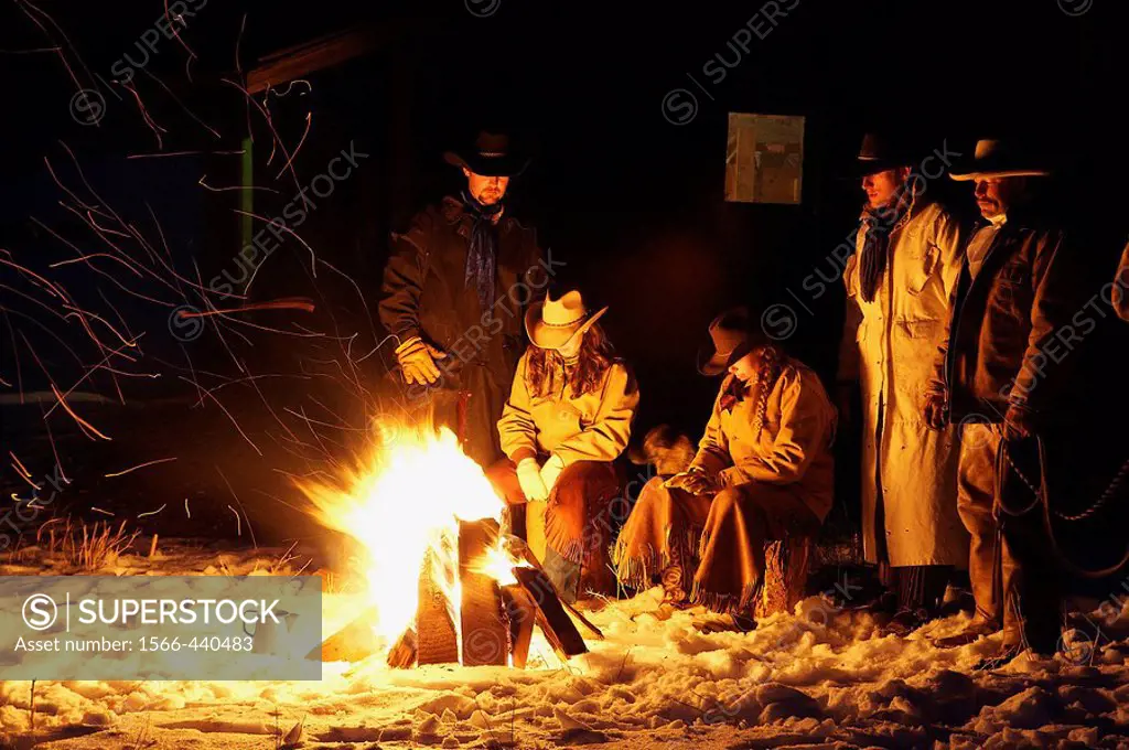 Wranglers gathered by the evening fire in the snow, Shell, Wyoming. Usa