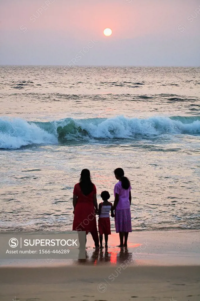 Women and child watching sunset at Lighthouse beach, Kerala, India