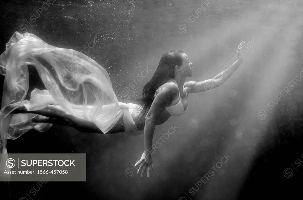 Girl swimming underwater, searching for the light.