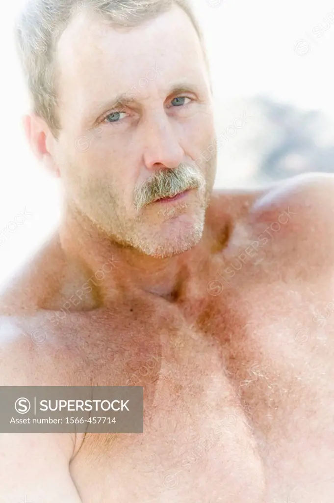 Close-up of a shirtless young man with a mustache.