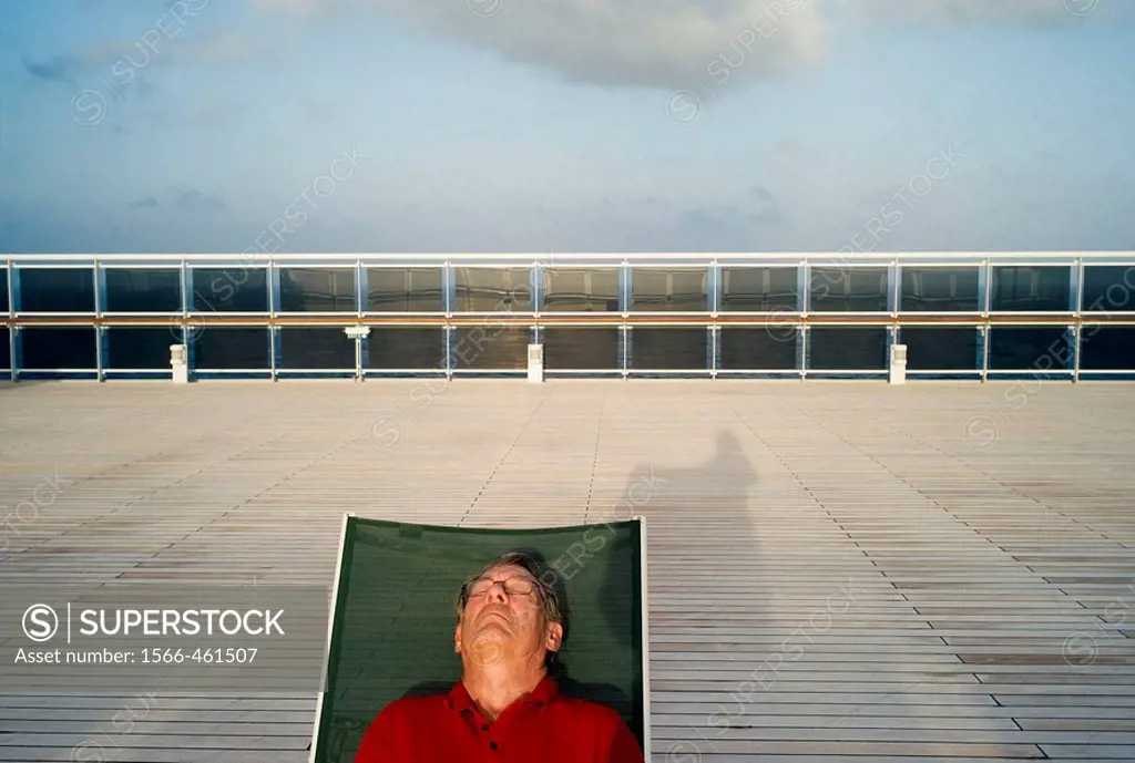 Man sunbathing on the deck of a cruise ship.