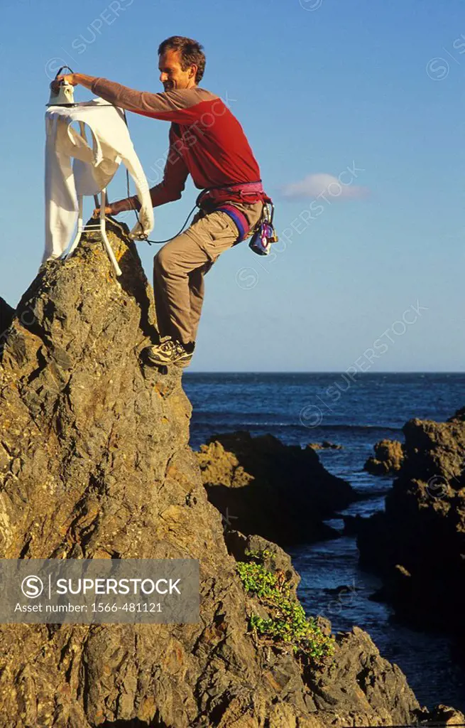 Extreme ironing, ironing a shirt on top of a rock pinnacle Houghton Bay Wellington New Zealand