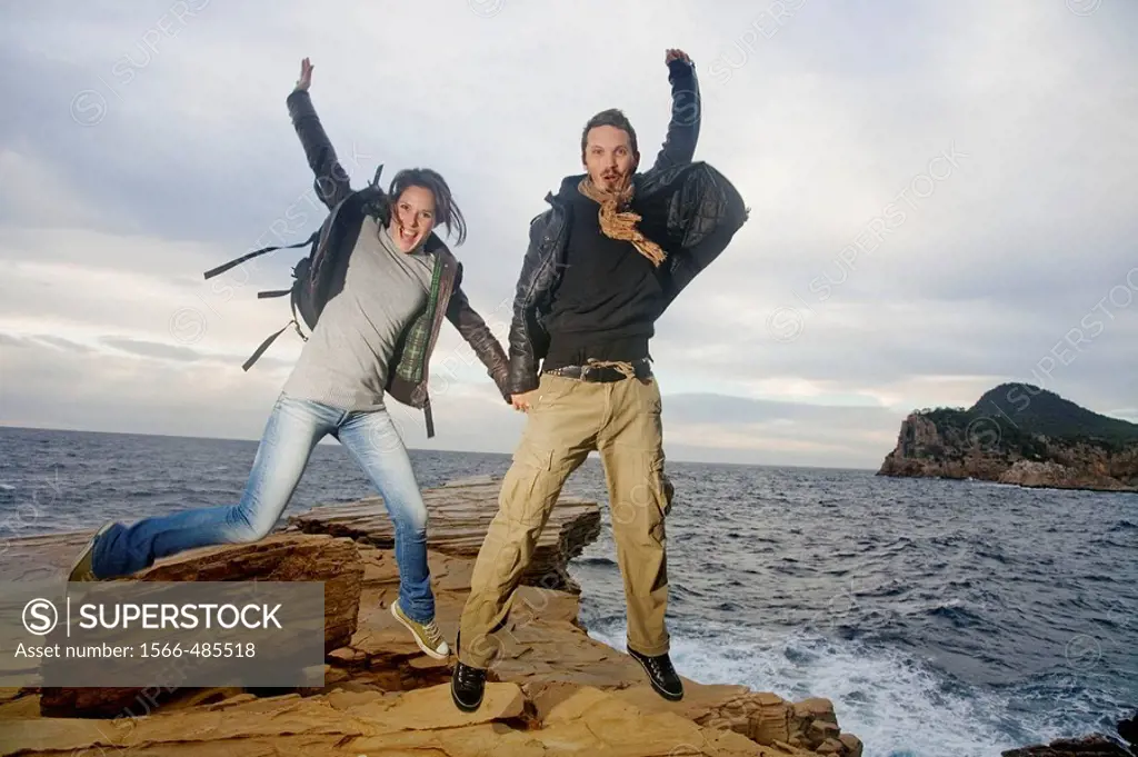 Couple jumping in a cliff by the sea