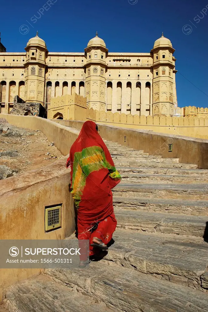 Woman in orange sari walking up to Amber Fort  Jaipur  India