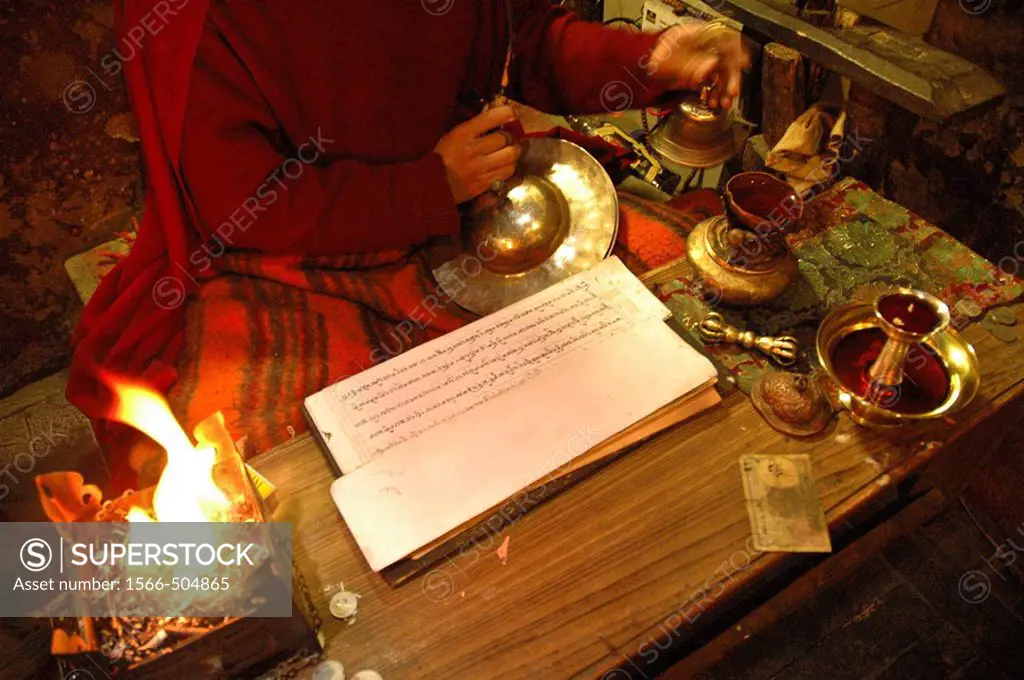 The hands of a monk chanting with a religious text and burning incense Tiksey, Ladakh, India