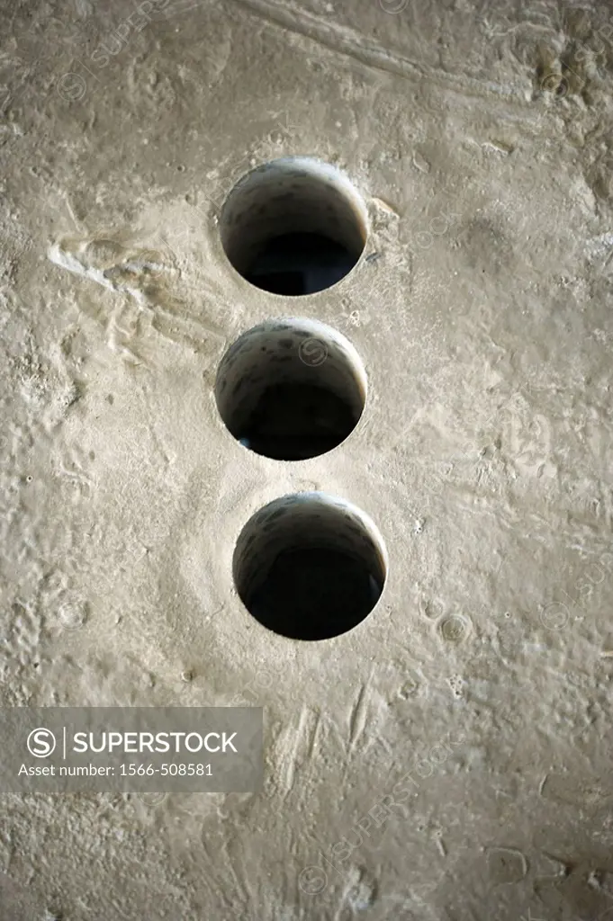 Three holes bored into cement floor
