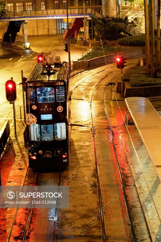 Hong Kong tram (seen from above) stopping at a station in the night besides a red light in Causeway Bay during a rainy day, Hong Kong Island, China, E...