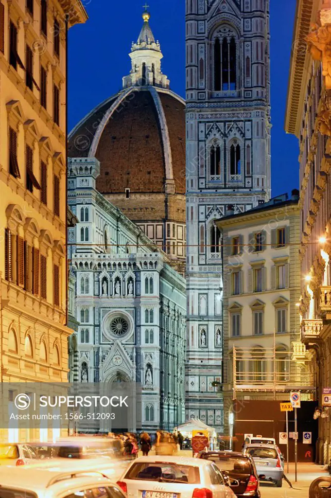 Duomo, Cathedral Santa Maria del Fiore and Campanile di Giotto seen from the street with people walking and cars parked at streetsite and at the night...