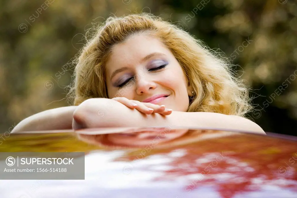 Daydreaming young woman on top of a car
