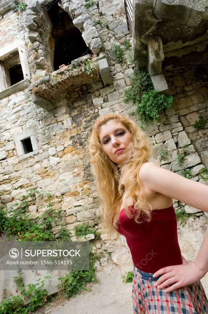 Young woman in Red corset posing in front of old Mediterranean building