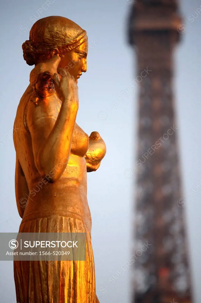 Closed up view of a gilded bronze statues on the central square of the Palais de Chailot with Eiffel Tower in background, Paris. France