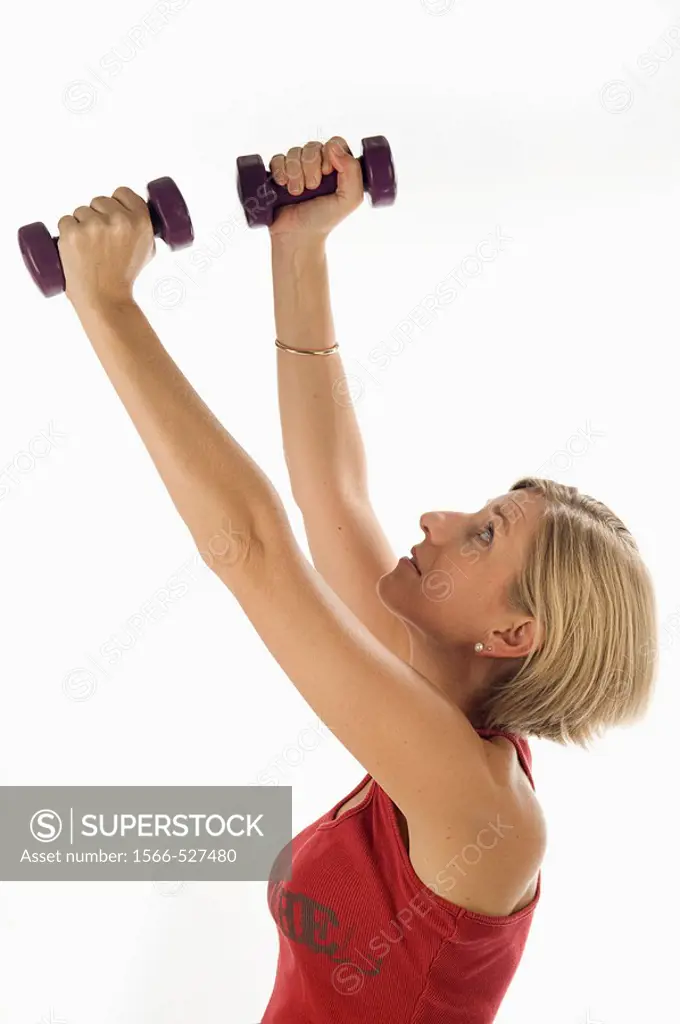 Young woman, blonde, exercising with weights in the gym to get fit.