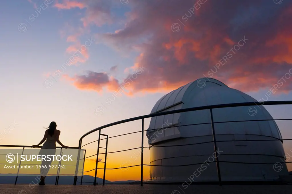 Young woman is standing next to space observatory telescope dome in sunset
