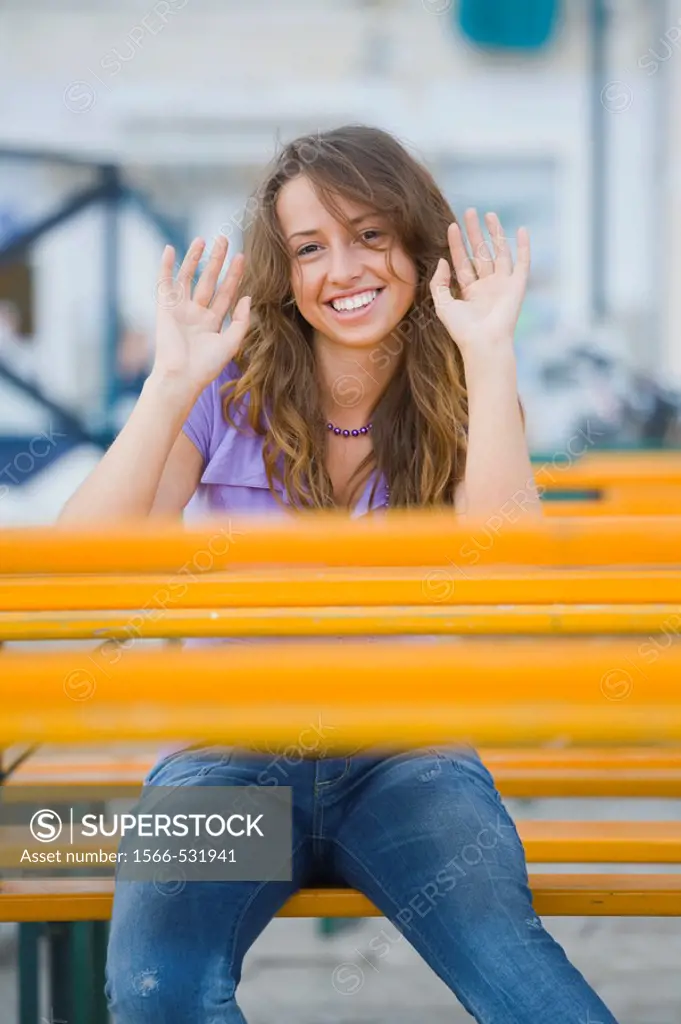 Young woman sitting behind Orange table acting ´hands up´