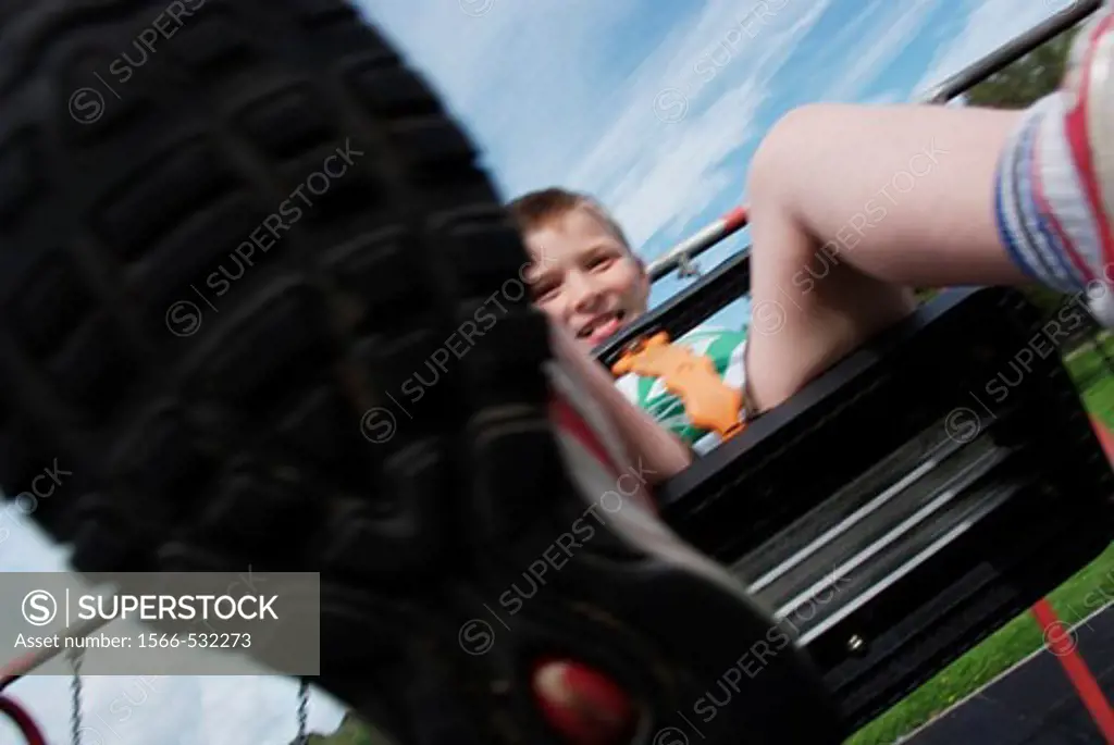 8 year boy with silly expression playing on swing, from below