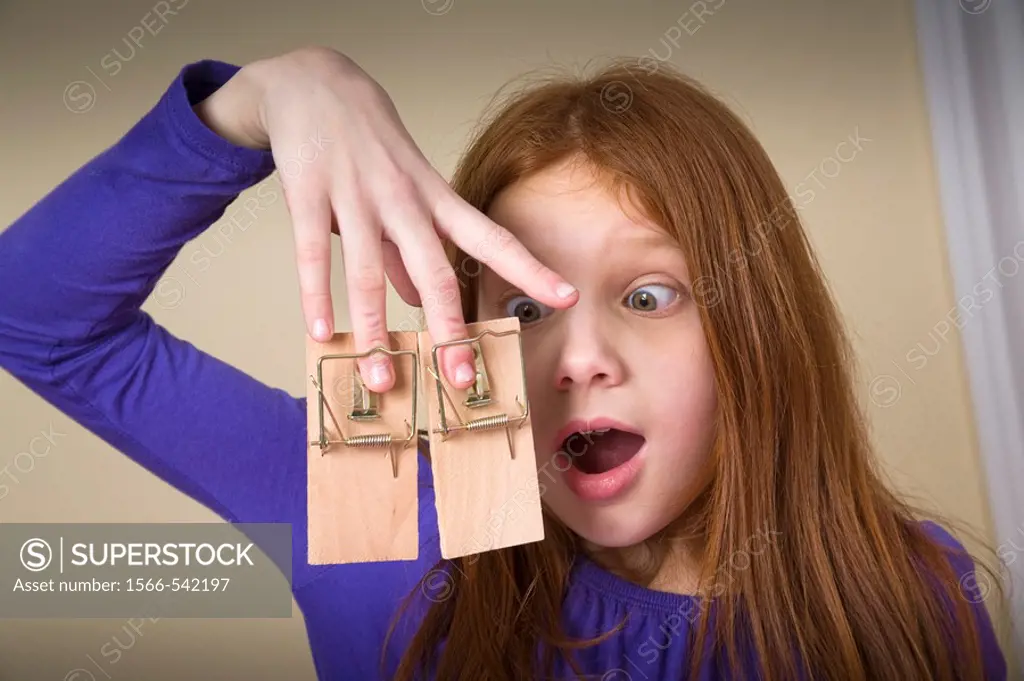 Preteen redhead girl with mousetraps on her fingers