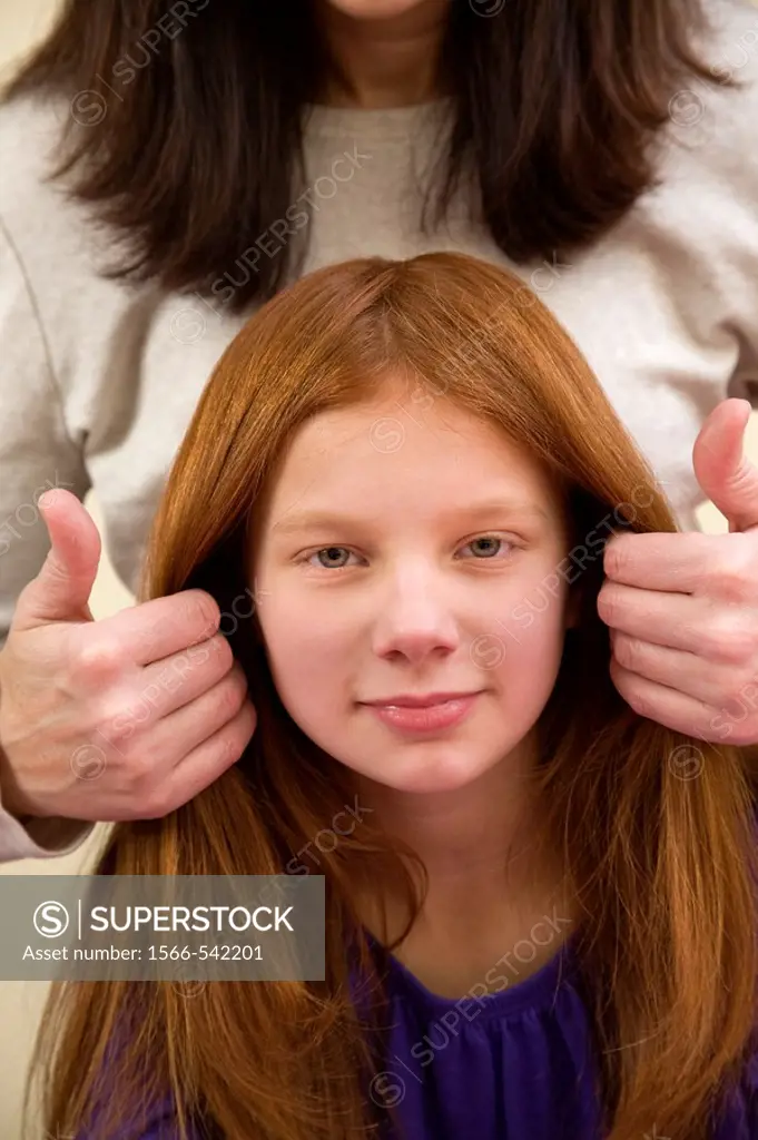 Mother fixing the hair of her preteen redhead daughter