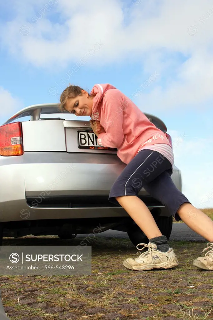 a woman pushing a broken down car