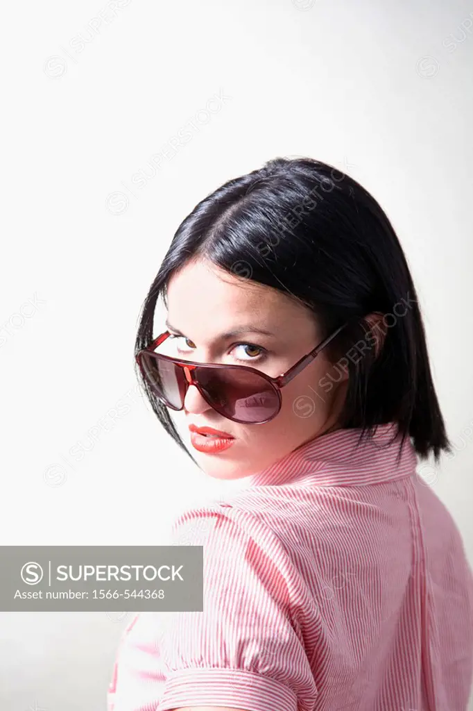 Portrait of a brunette woman with sunglasses in a studio shot