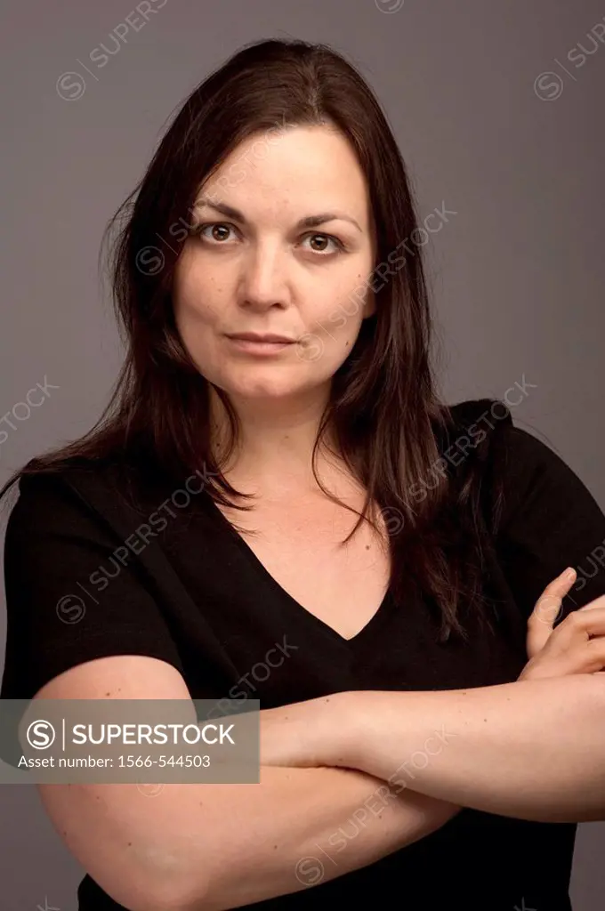 A stern looking 30 year old woman with her arms folded looking serious