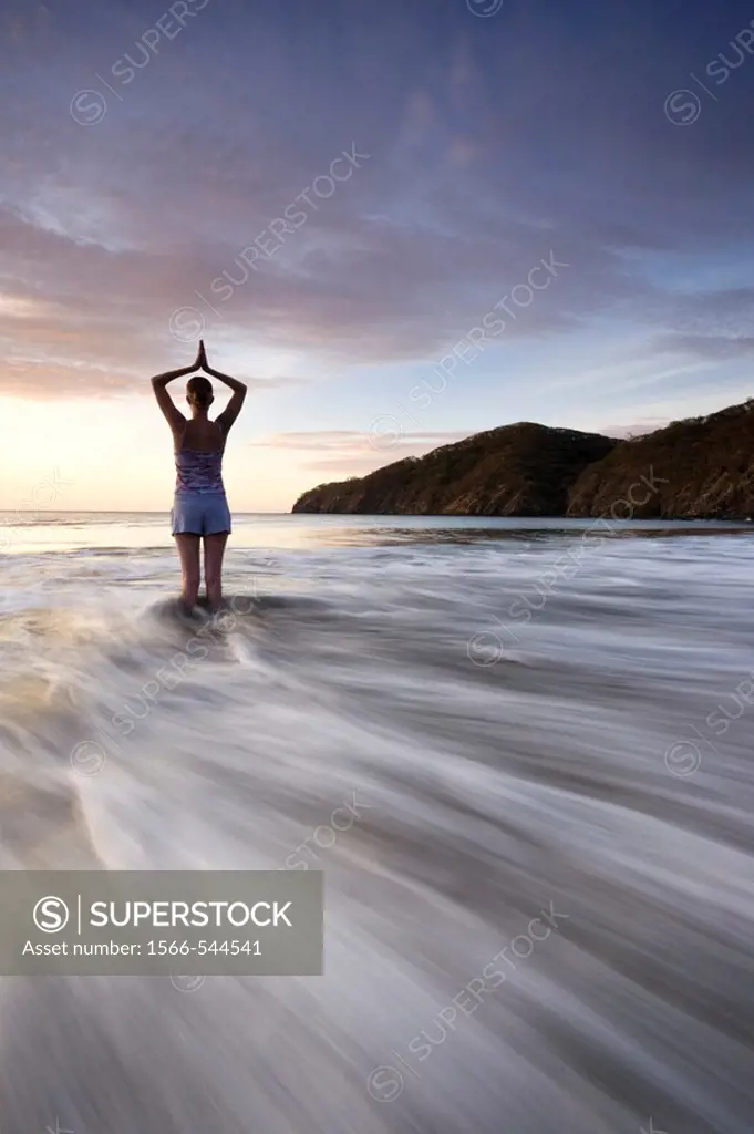 Silhouette of young woman doing yoga at the beach during sunset in Playas del Coco, Costa Rica