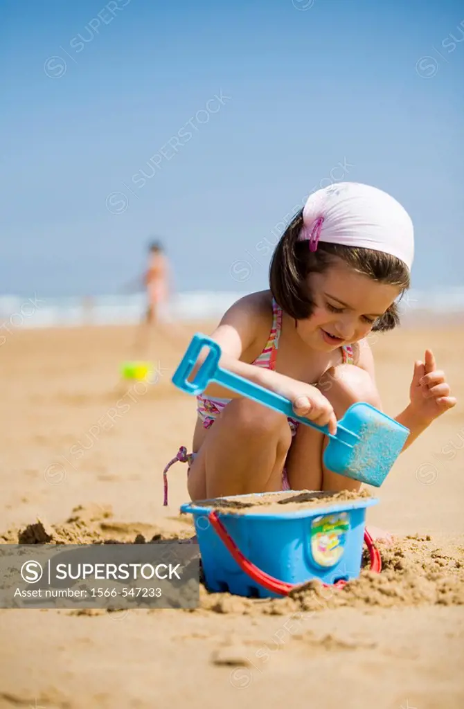 Niña jugando con la arena en la playa