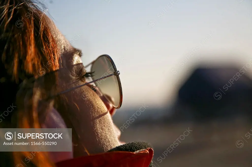 Mujer sentada y relajada tomando los ultimos rayos de sol del dia