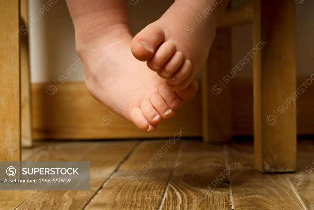 Stock photo of a toddlers bare feet dangling off a chair