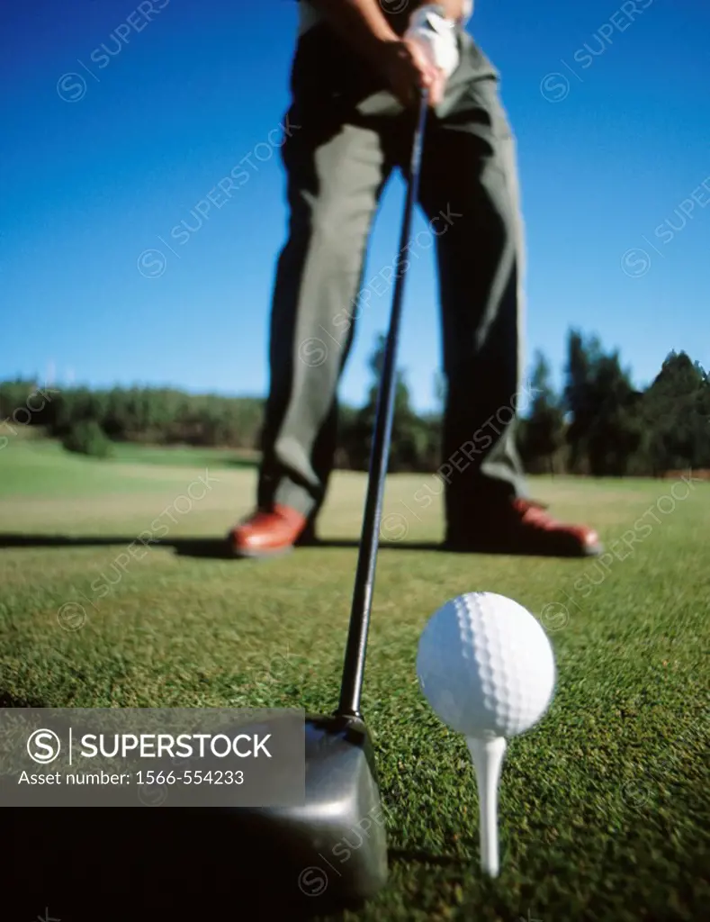 Golfer about to hit golf ball off of tee with driver, low angle