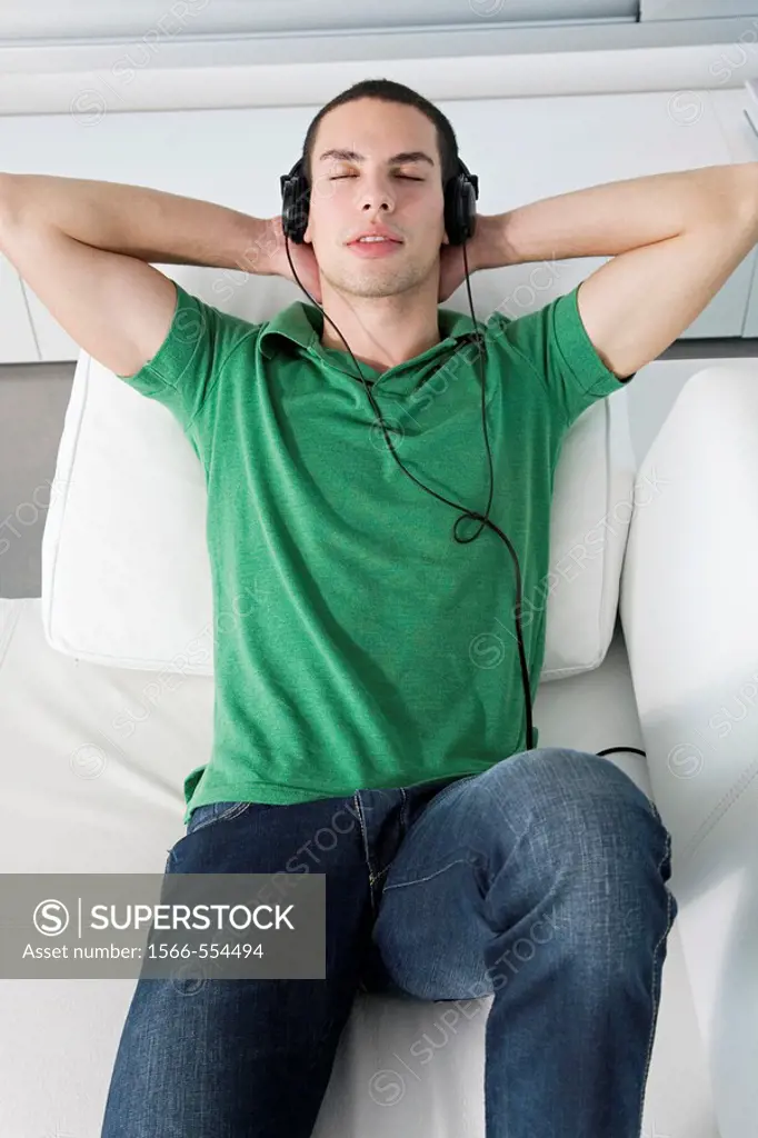 Young man relaxed lying on the couch listening to music